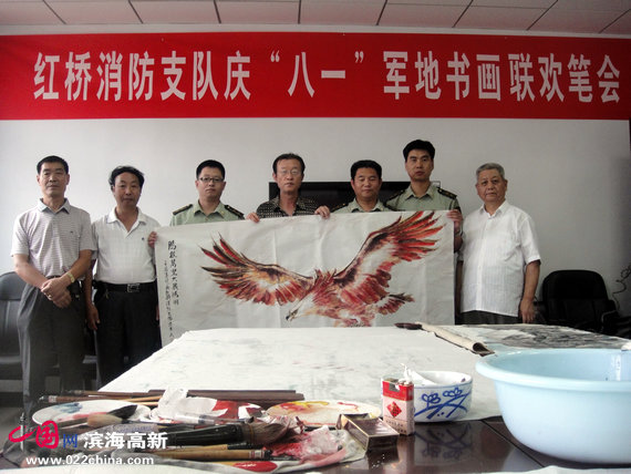 军民在要华民的《大红鹰》画作前合影。