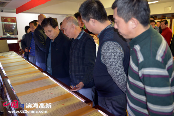 天津滨海高新区工委宣传部部长王会臣在观赏李玉海创作的小楷长卷。