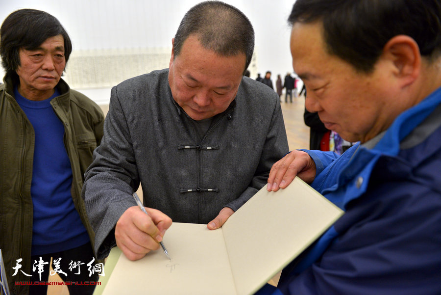 中国梦·天容海色——马孟杰书法作品展在天津美术馆举办。图为马孟杰为观众在其书法集上签名留念。