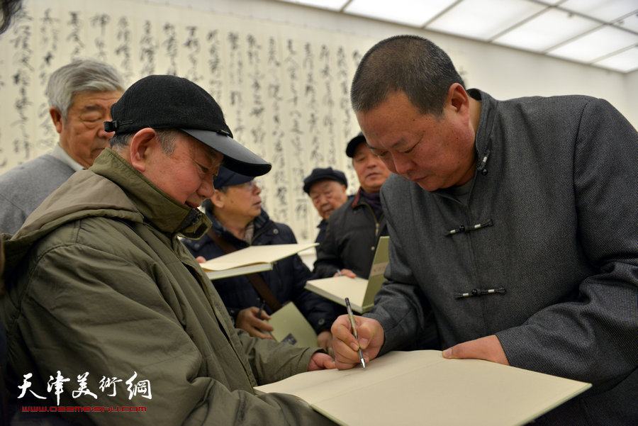 中国梦·天容海色——马孟杰书法作品展在天津美术馆举办。图为马孟杰为观众在其书法集上签名留念。