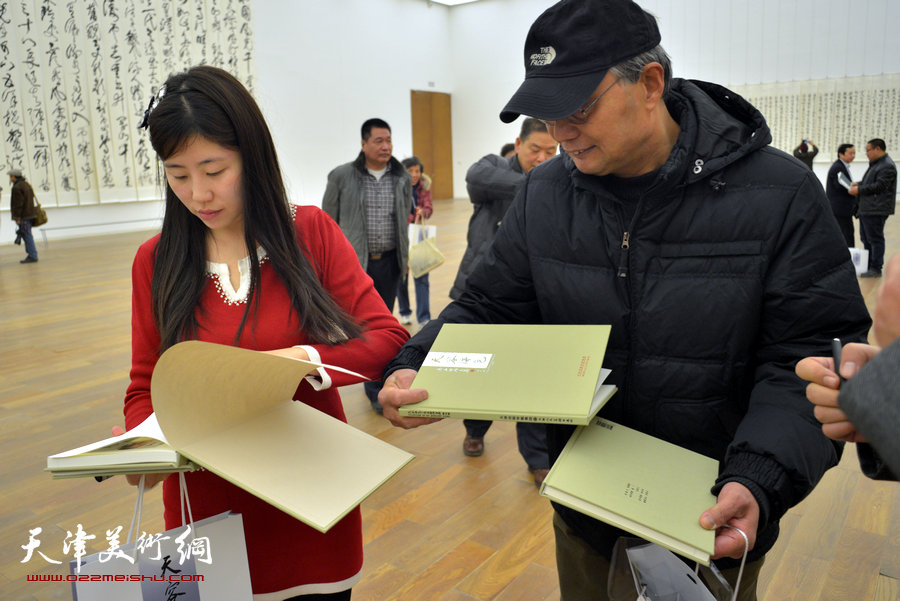 中国梦·天容海色——马孟杰书法作品展在天津美术馆举办。图为马孟杰为观众在其书法集上签名留念。