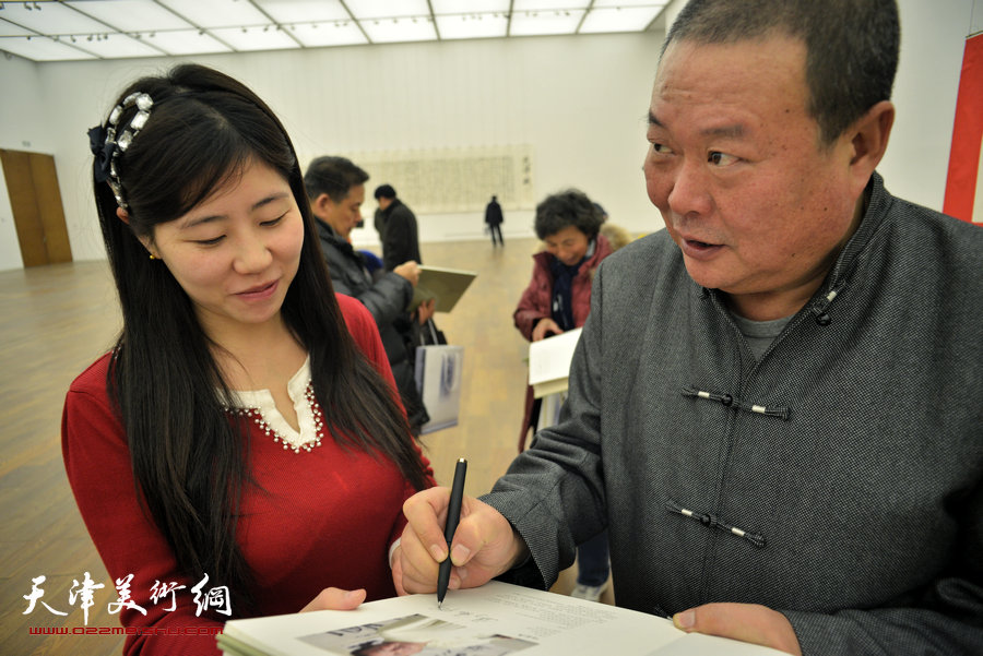 中国梦·天容海色——马孟杰书法作品展在天津美术馆举办。图为马孟杰为观众在其书法集上签名留念。