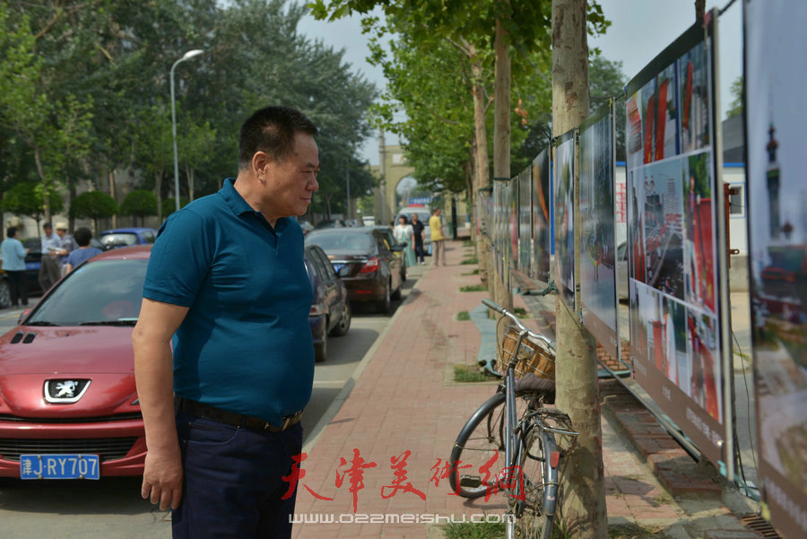 第四届“天穆杯”书画摄影展在北辰区天穆东苑举行，图为观众阅读《天穆书画摄影报》。