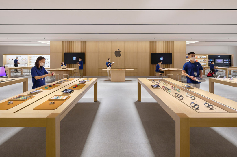 Apple 武汉零售店内，Specialist 专家正在设置产品展示桌上的 Apple 设备。