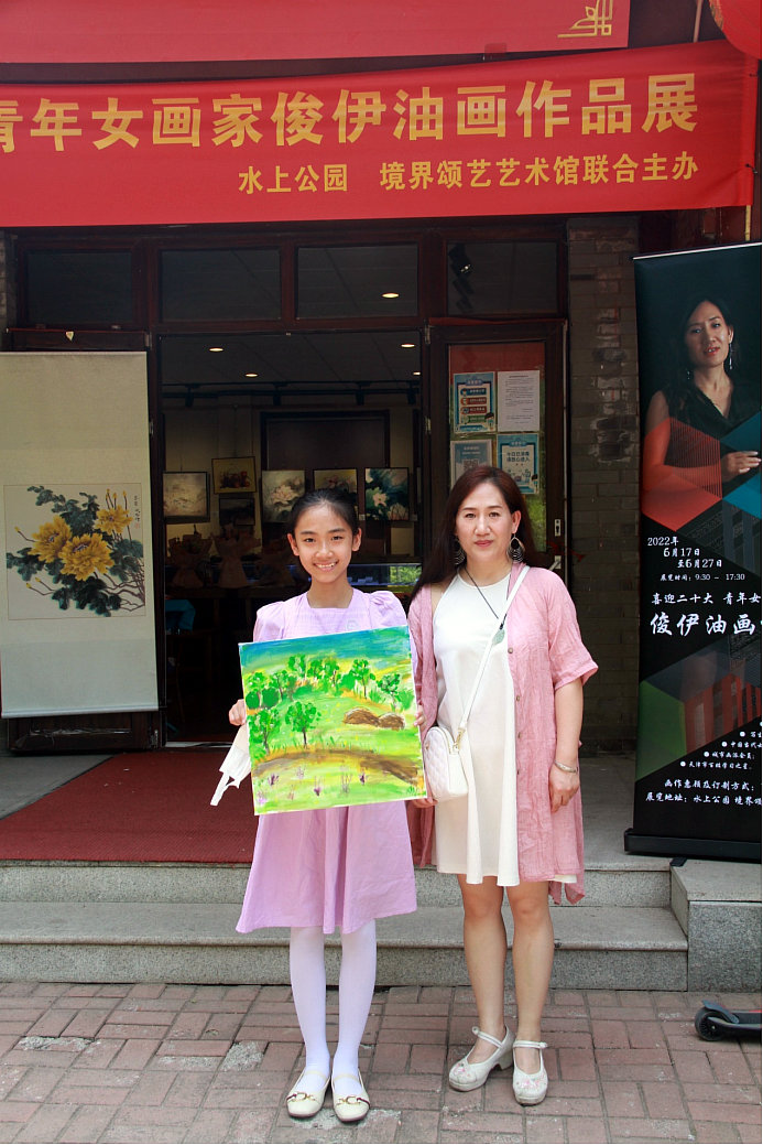 学生王钰涵在画展现场展示写生的作品